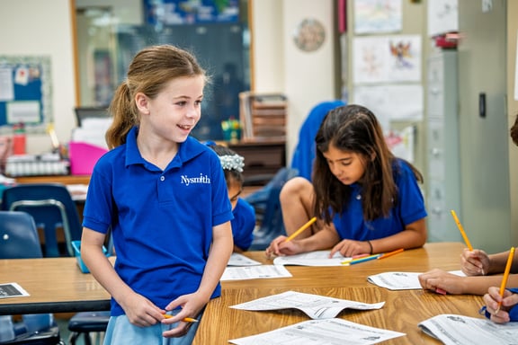 Student talks with classmates during a group activity in a lively, collaborative classroom